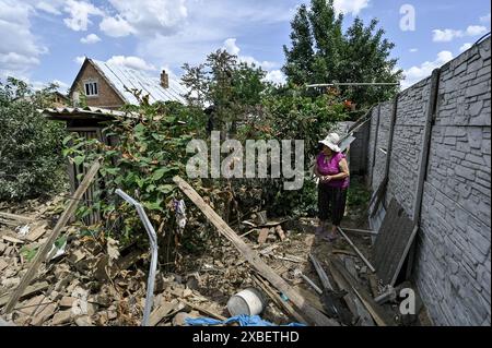 RÉGION de ZAPORIZHZHIA, UKRAINE - 10 JUIN 2024 - une femme âgée marche à travers les décombres d'une maison partiellement détruite par une attaque de drone russe, Orikhiv, région de Zaporizhzhia, sud-est de l'Ukraine. Banque D'Images