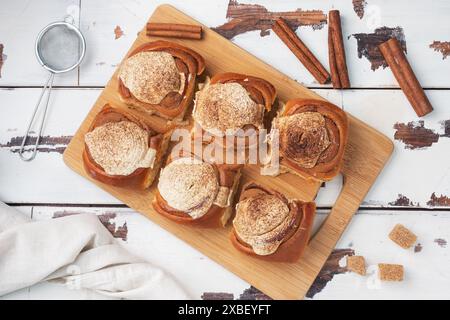 Kanelbulle petits pains à la cannelle avec crème au beurre sur une table en bois rustique. Viennoiseries maison, vue de dessus, espace photocopie. Banque D'Images
