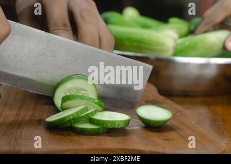 les concombres verts sont coupés avec un couteau dans la cuisine. gros plan concombres verts dans les mains de la cuisine gros plan coupé en tranches Banque D'Images