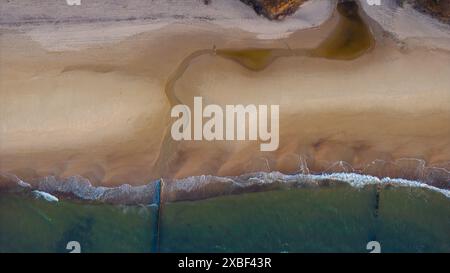 Plage vue d'en haut : sable ensoleillé, océan calme. Banque D'Images