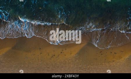 Tir de drone : rivage de sable vide, lumière du soleil dorée. Banque D'Images