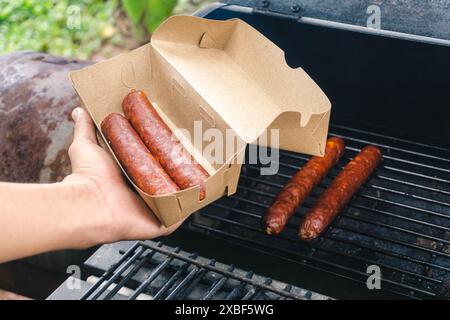 les saucisses fumées qui sont déjà cuites sont emballées par le cuisinier, concept de petite entreprise Banque D'Images