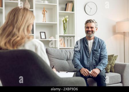 Homme patient pendant la séance de thérapie avec femme blonde psychologue en clinique médicale Banque D'Images