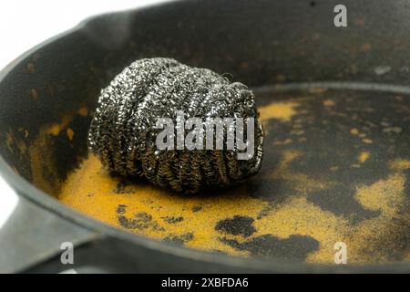 Épurateurs de laine d'acier ou épurateurs d'acier inoxydable sur le dessus d'une poêle en fonte rouillée isolé sur fond blanc Banque D'Images