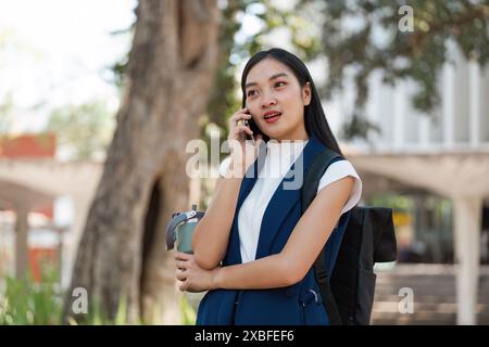 Jeune femme professionnelle embrassant Business Eco Lifestyle en plein air, parler sur mobile, mode durable, environnement vert urbain, Eco moderne Banque D'Images