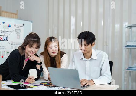 Jeune équipe créative collaboration sur le projet de conception d'interface utilisateur UX dans un environnement de bureau moderne avec des ordinateurs portables et des esquisses Banque D'Images