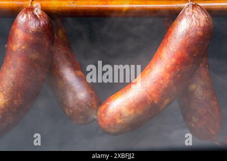 Saucisses accrochées sur le rack dans un fumoir avec une fumée épaisse, fermé Banque D'Images