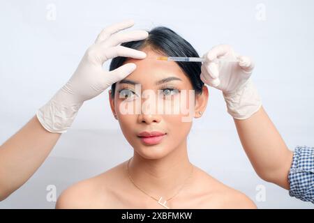 Charmante femme asiatique avec updo subissant une injection de Botox pour resserrer la peau Banque D'Images