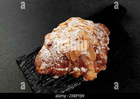 Croissant aux amandes. pâte feuilletée, délicate crème frangipane aux amandes, enrichie de beurre. Sur le dessus, le croissant a un soupçon de flocons d'amande et de pow Banque D'Images