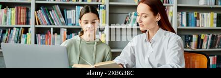 Redhead tuteur enseigne à une adolescente dans une bibliothèque, à la fois engrossés dans un ordinateur portable Banque D'Images