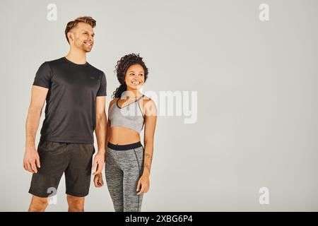 Un homme et une femme, tous deux en tenue active, debout côte à côte sur un fond gris dans un décor de studio. Banque D'Images