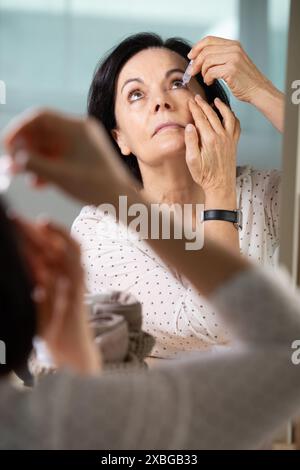 femme âgée mettant en gouttes oculaires Banque D'Images