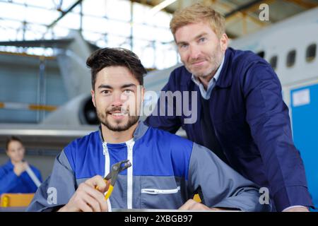 Deux mécaniciens travaillant sur un petit avion dans un hangar Banque D'Images