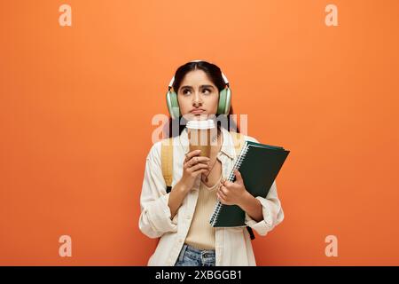 Jeune femme indienne dans des écouteurs appréciant le café. Banque D'Images