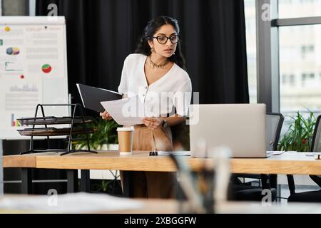 Une femme indienne bien serrée se tient debout avec assurance devant un bureau. Banque D'Images