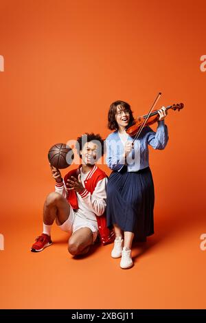 De jeunes amis multiculturels posent avec un ballon de basket et un violon dans un studio élégant. Banque D'Images