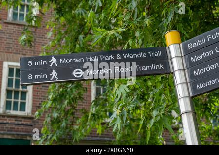 LONDRES - 10 JUIN 2024 : panneau de direction piétonne pour Morden Hall Park & Wandle Trail ; tramway de Morden Road Banque D'Images