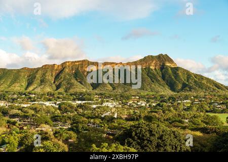 Une vue aérienne capture une montagne entourée d'arbres et de maisons, formant un paysage naturel pittoresque avec des éléments comme les nuages, le ciel et l'herbe Banque D'Images