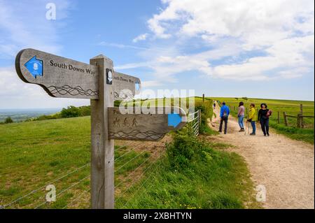 Panneau en bois donnant des directions à trois voies sur South Downs Way avec un groupe de marcheurs près de Clayton, West Sussex, Angleterre. Banque D'Images