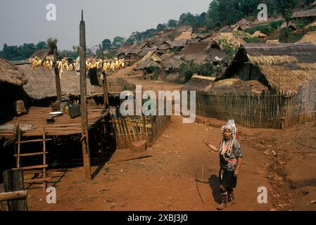 Akha village dans les montagnes du nord de la Thaïlande. Femme en costume traditionnel indigène de tous les jours, sa maison a une plate-forme surélevée où le maïs sèche au soleil. Sa maison est une maison sur pilotis, tandis que beaucoup d'autres sont des maisons basses, c'est-à-dire construites sur le sol. Tribu Akha Hill peuple indigène du nord de la Thaïlande des années 1995 1990 se Asie HOMER SYKES Banque D'Images