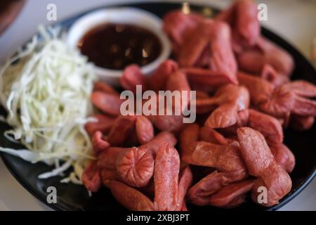 Saucisses frites rouges avec sauce sucrée sur une assiette avec du chou. C'est une célèbre cuisine de rue thaïlandaise Banque D'Images