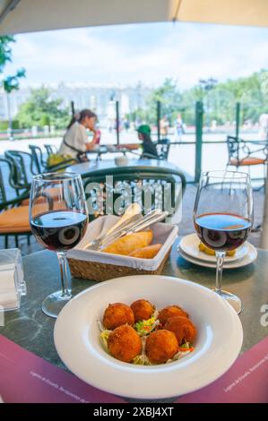 Servir les croquettes et deux verres de vin rouge dans une terrasse. Oriente, Madrid, Espagne. Banque D'Images