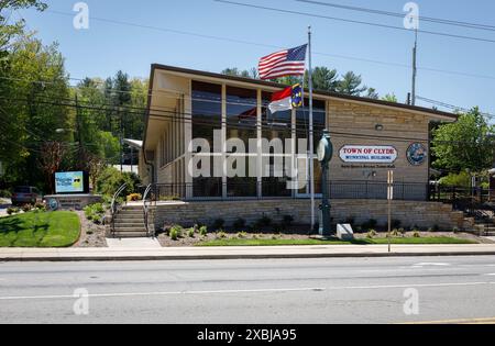 Clyde, NC, États-Unis-4 mai 2023 : bâtiment municipal de la ville, avec des panneaux, des drapeaux et une horloge sur piédestal devant. Banque D'Images