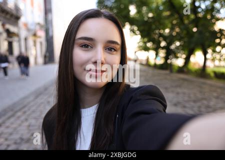 Belle jeune blogueuse de voyage prenant selfie à l'extérieur Banque D'Images