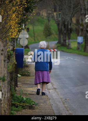 Une vieille dame française marchant et transportant une baguette dans un sac. Banque D'Images