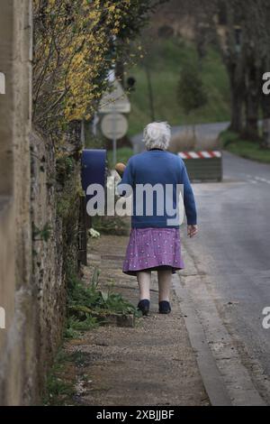 Une vieille dame française marchant et transportant une baguette dans un sac. Banque D'Images