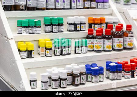 Osijek Croatie - 7 06 2024 : salon de la santé et de la beauté. diverses bouteilles d'huile essentielle de différentes couleurs et tailles, soigneusement affichées sur des étagères blanches. Th Banque D'Images