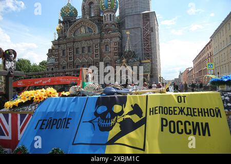 Un cercueil recouvert de tissu aux couleurs du drapeau ukrainien avec un squelette couché sur le dessus avec des inscriptions « pour l'Europe gay de la Russie invaincue » à Pétersbourg lors d'un rassemblement pro-guerre créé par des inconnus le jour de la Russie. Des inconnus organisèrent un rassemblement militaire près de l'église orthodoxe du Sauveur sur sang versé à Pétersbourg le jour de la Russie. Une voiture avec des photographies du président américain Joe Biden et du président ukrainien Vladimir Zelensky avec des inscriptions les insultant a été arrêtée par la police de la circulation. La voiture avait une remorque en forme de cercueil avec une photographie de Fede allemand Banque D'Images