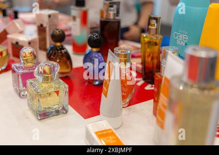 Osijek Croatie - 7 06 2024 : divers flacons de parfum et tubes de lotion sont affichés sur une table rouge. Les bouteilles sont de différentes formes et tailles, et Banque D'Images