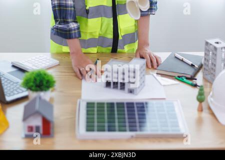 Les ingénieurs examinent les plans des architectes pour préparer l’installation de panneaux solaires et d’éoliennes sur le bâtiment afin de produire efficacement de l’électricité Banque D'Images