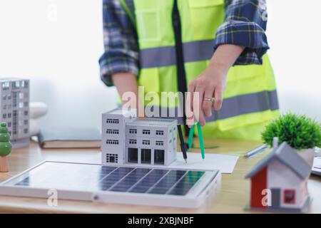 Les ingénieurs examinent les plans des architectes pour préparer l’installation de panneaux solaires et d’éoliennes sur le bâtiment afin de produire efficacement de l’électricité Banque D'Images