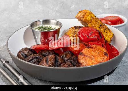 Légumes grillés sur une assiette, maïs et poivrons, champignons et sauce. Copier l'espace Banque D'Images
