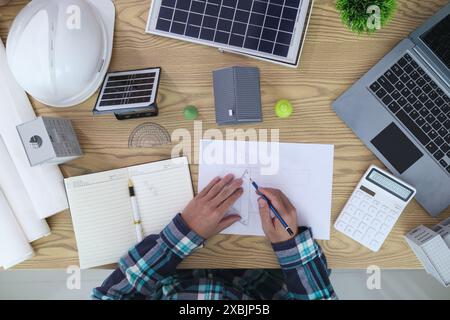 Les ingénieurs examinent les plans des architectes pour préparer l’installation de panneaux solaires et d’éoliennes sur le bâtiment afin de produire efficacement de l’électricité Banque D'Images