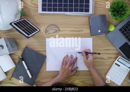 Les ingénieurs examinent les plans des architectes pour préparer l’installation de panneaux solaires et d’éoliennes sur le bâtiment afin de produire efficacement de l’électricité Banque D'Images