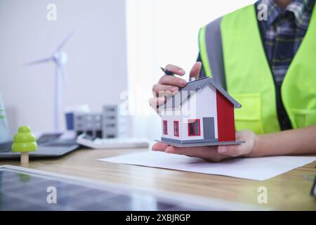 Les ingénieurs examinent les plans des architectes pour préparer l’installation de panneaux solaires et d’éoliennes sur le bâtiment afin de produire efficacement de l’électricité Banque D'Images