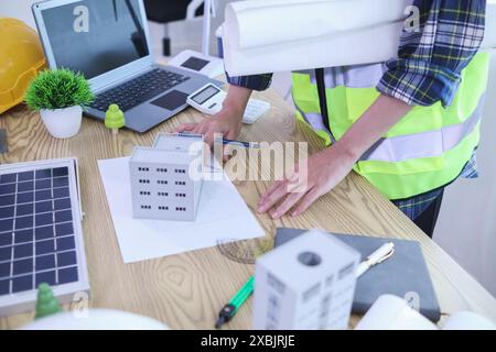 Les ingénieurs examinent les plans des architectes pour préparer l’installation de panneaux solaires et d’éoliennes sur le bâtiment afin de produire efficacement de l’électricité Banque D'Images