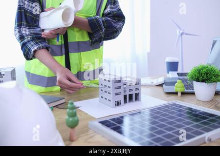 Les ingénieurs examinent les plans des architectes pour préparer l’installation de panneaux solaires et d’éoliennes sur le bâtiment afin de produire efficacement de l’électricité Banque D'Images