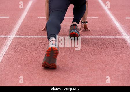 jambes de sportif professionnel en position de départ, courir le long de la piste caoutchoutée au stade extérieur Banque D'Images