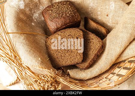 Pain de seigle Borodinsky avec thym dans un panier avec des oreilles d'orge sur un tissu de toile. Photo de haute qualité Banque D'Images