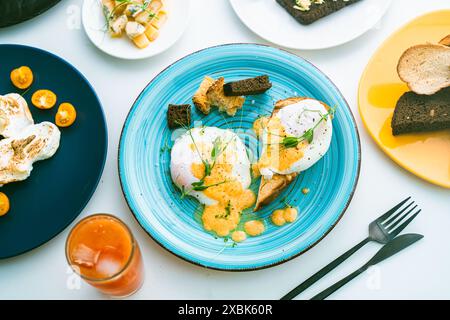 Oeufs, Benoît sur pain grillé et avocat sur une tranche de pain de seigle, fromage et un verre de jus d'orange sur la table. Foyer sélectionné. Photo de haute qualité Banque D'Images