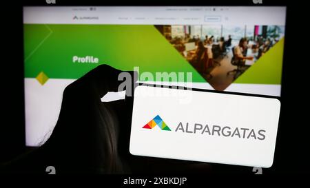 Personne tenant un smartphone avec le logo de la société brésilienne de chaussures Alpargatas S.A. en face du site Web. Concentrez-vous sur l'affichage du téléphone. Banque D'Images
