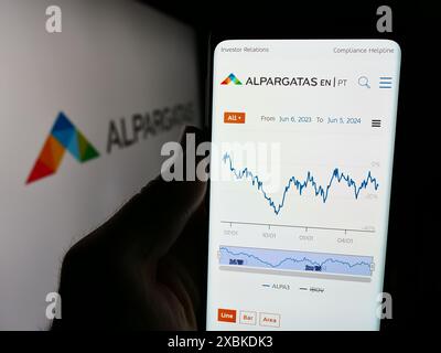 Personne tenant le smartphone avec la page Web de la société brésilienne de chaussures Alpargatas S.A. devant le logo. Concentrez-vous sur le centre de l'écran du téléphone. Banque D'Images