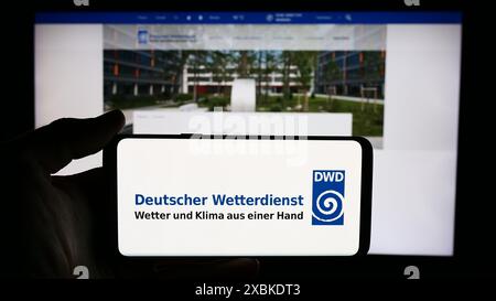 Personne tenant un téléphone portable avec le logo du service météorologique allemand Deutscher Wetterdienst (DWD) en face de la page web. Concentrez-vous sur l'affichage du téléphone. Banque D'Images