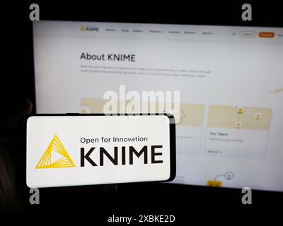 Personne tenant le téléphone portable avec le logo de la société de logiciels d'analyse KNIME AG devant la page Web de l'entreprise. Concentrez-vous sur l'affichage du téléphone. Banque D'Images
