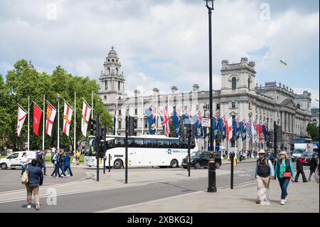 Les gens dans la rue sur la place du Parlement. Des drapeaux colorés volent des mâts de drapeau sur Parliament Square Garden. Westminster, Londres, Angleterre, Royaume-Uni Banque D'Images