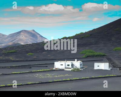 Une maison blanche sur fond noir avec des montagnes et un ciel bleu en arrière-plan, arrecife, Lanzarote, îles Canaries, Espagne Banque D'Images